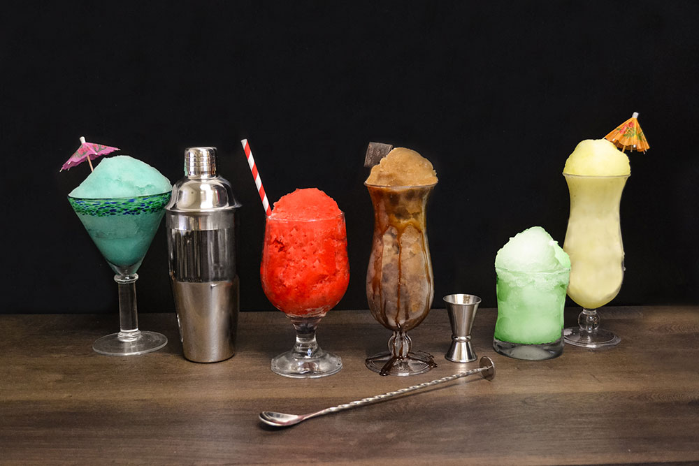 a row of different size and shape glasses with multiple flavors of italian ice