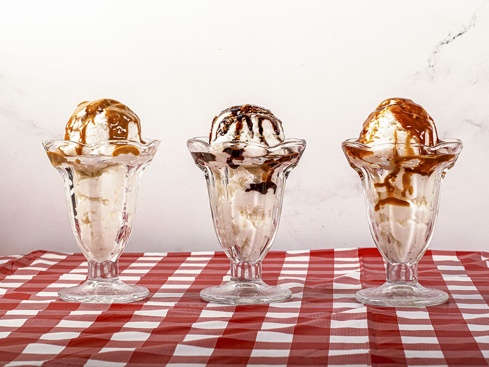 three sundaes in glasses with caramel and chocolate sauces